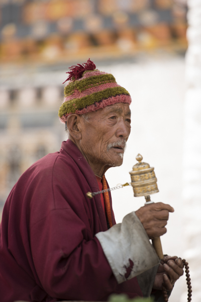 Buddhist spinning a hand held prayer wheel