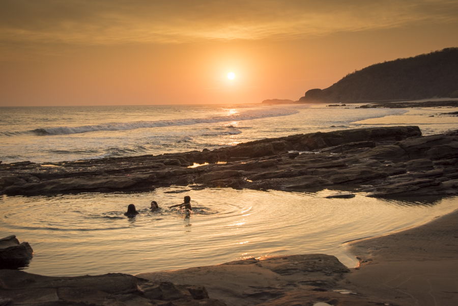 Nicaraguan family enjoying a swim in the tide pools at sunset