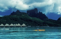Kayakers next to luxury huts, Bora Bora